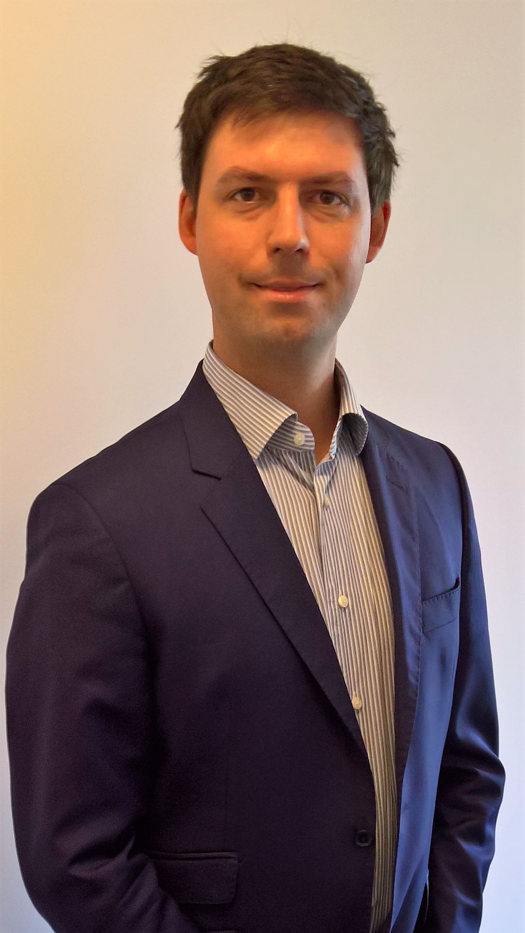 Person wearing a navy blue suit jacket over a striped dress shirt.